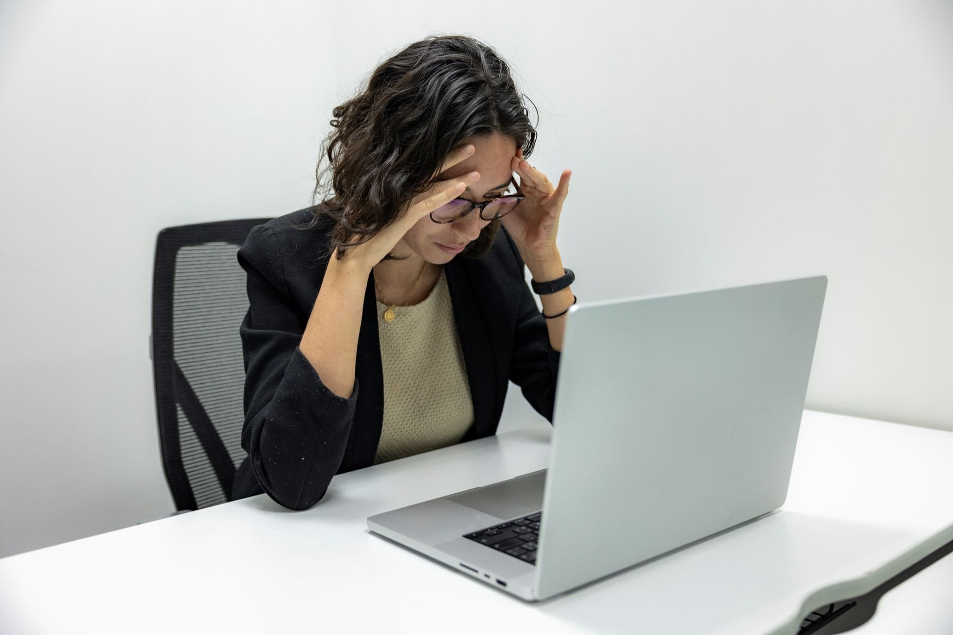 Jonge vrouw met hoofdpijn en vermoeidheid achter haar laptop op kantoor Jonge vrouw met hoofdpijn en vermoeidheid achter haar laptop op kantoor